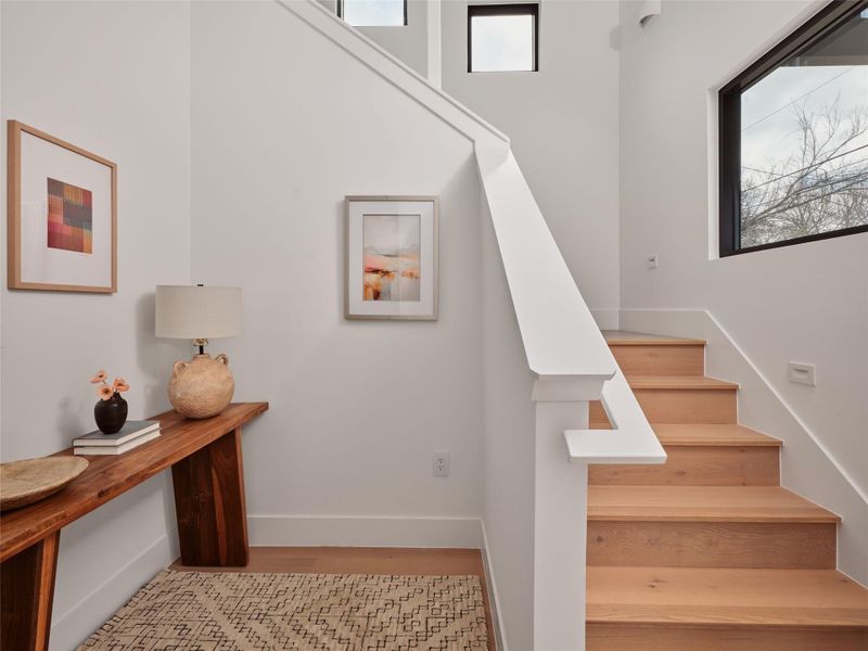 Stairs featuring plenty of natural light and wood finished floors