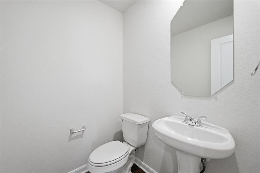 White pedestal sink with a chrome faucet, accented by an octagonal wall mirror