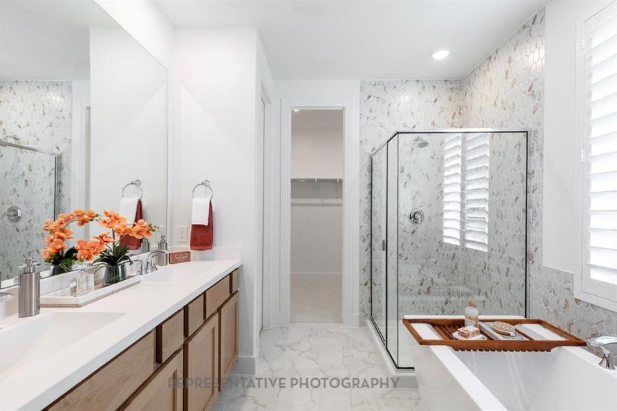 Full bathroom with a marble finish shower, a freestanding tub, a walk in closet, double vanity, and light marble finish floors