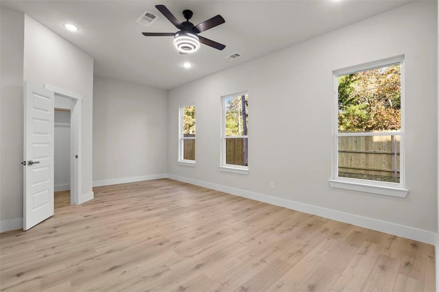 Unfurnished bedroom featuring multiple windows, ceiling fan, and light hardwood / wood-style flooring