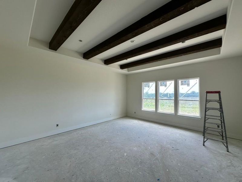 Tray ceiling featuring dark wood beams and recessed lighting