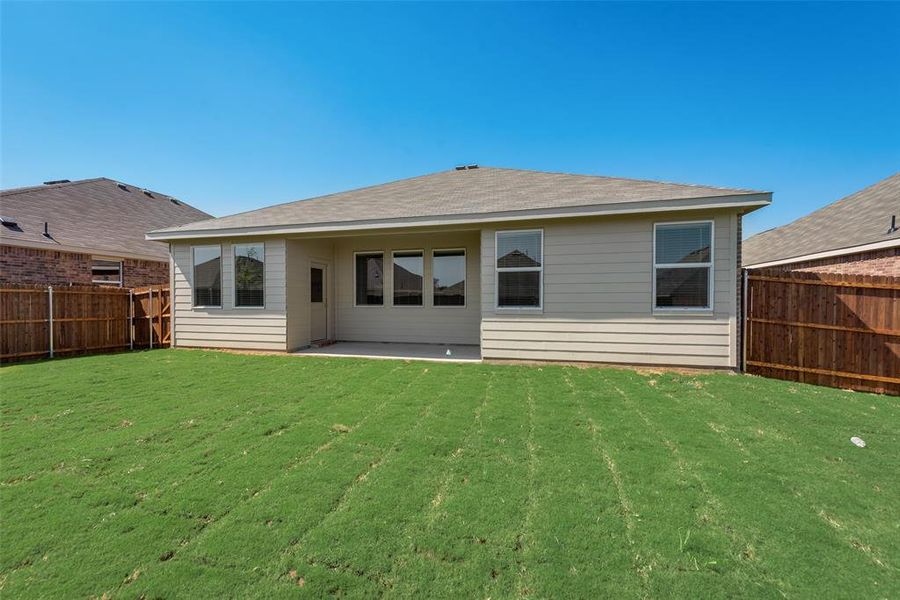 Rear view of property featuring a lawn and a patio