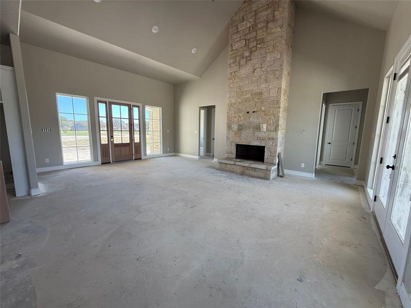 Unfurnished living room with a fireplace, concrete floors, and vaulted ceiling