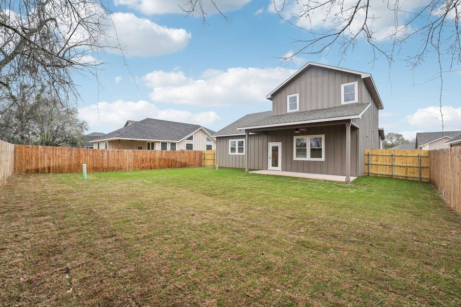 Rear view of property featuring a lawn, a fenced backyard, and a ceiling fan Rear view of property featuring a lawn, a fenced backyard, and a ceiling fan