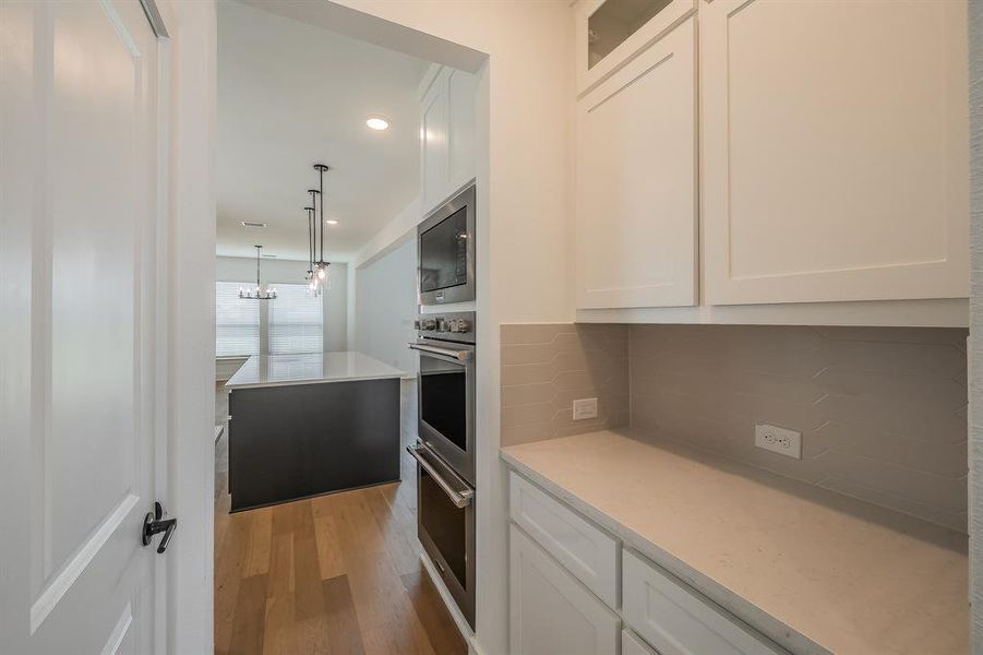 The kitchen features light wood flooring, a dark kitchen island with a light countertop, and pendant lighting