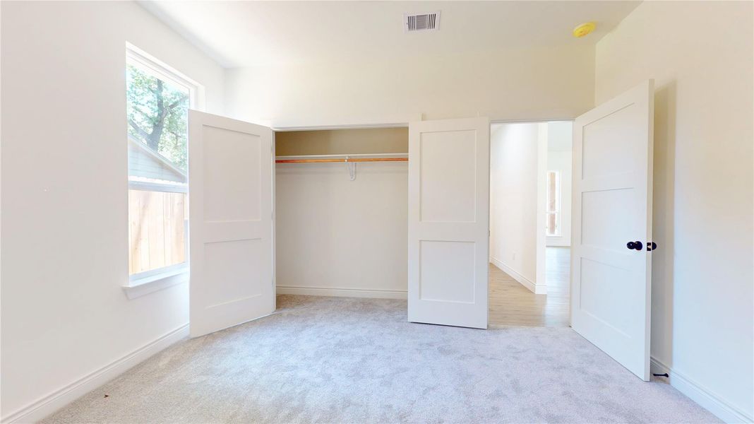 Bright secondary bedroom featuring plush carpet, ample closet space, and a serene, neutral palette.