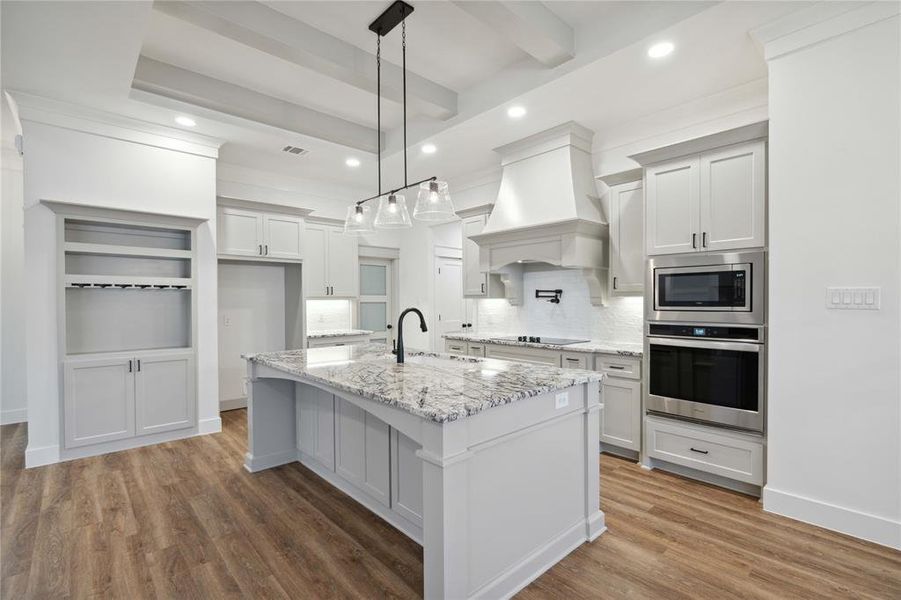 Kitchen featuring white cabinetry, an island with sink, stainless steel appliances, custom exhaust hood, and hardwood / wood-style floors