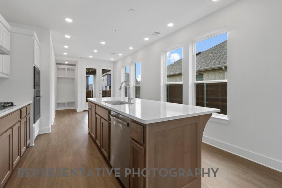 The kitchen is filled with natural light from its windows, creating a bright and inviting space for cooking and gathering.