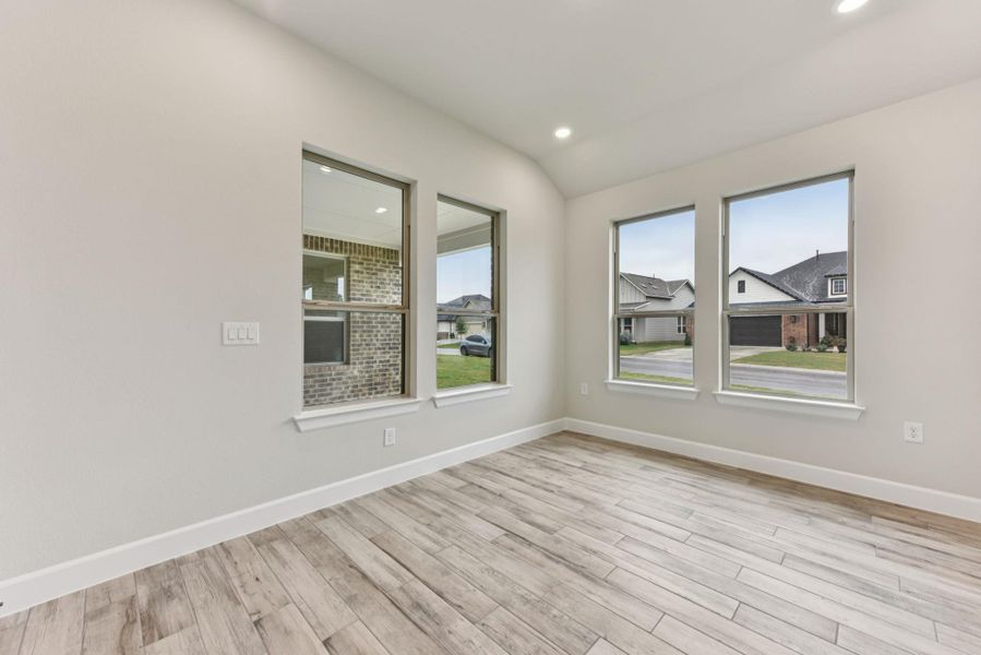 Empty room with light wood-style floors, lofted ceiling, recessed lighting, and a residential view