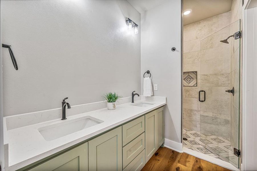 Bathroom featuring double vanity, dark wood finished floors, and a shower stall Bathroom featuring double vanity, dark wood finished floors, and a shower stall
