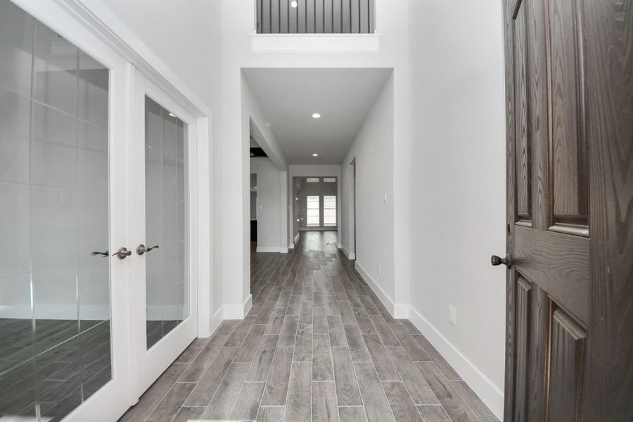 As you step into the threshold of this luxurious home, you'll soon be welcomed by an elegant glass door (to be installed). Inside, soaring ceilings amplify the spaciousness, while the refined wood-look tile flooring and oversized baseboards exude sophistication and charm. Sample photo of completed home with similar floor plan. Actual colors and selections may vary.