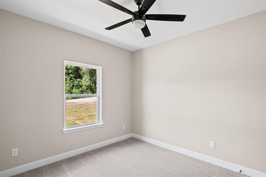 Bedroom featuring light gray wall paint, a single window, gray carpet flooring, white baseboards, and a ceiling fan with light