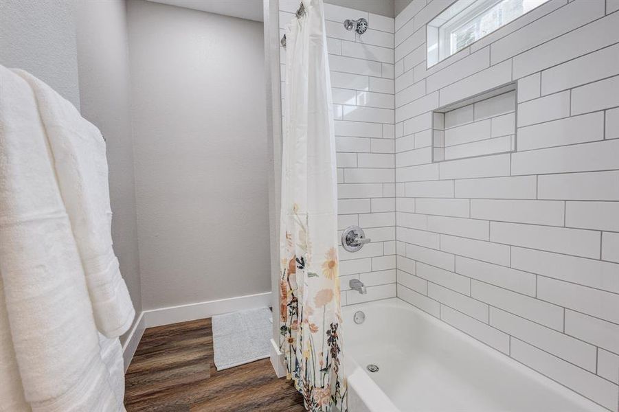 Bathroom with wood-type flooring and shower / bathtub combination with curtain