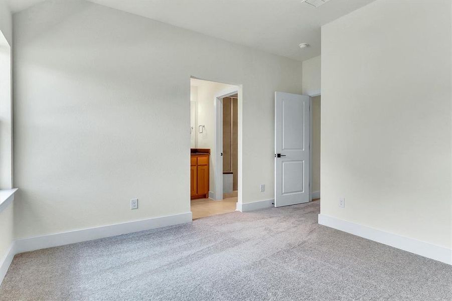Carpeted interior space featuring light-toned walls, white baseboards, and a window Carpeted interior space featuring light-toned walls, white baseboards, and a window