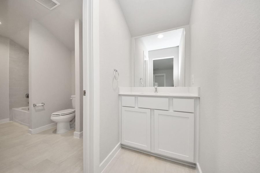 Experience convenience in the secondary bathroom, designed for Jack and Jill arrangements, now with a separate vanity area. This well-appointed space showcases stylish tile flooring, a bath/shower combo with an elegant tile surround, and light-stained wood cabinets. The beautiful light countertop adds a touch of sophistication, combining functionality and aesthetics seamlessly. Sample photo of completed home with similar floor plan. Actual colors and selections may vary. Experience convenience in the secondary bathroom, designed for Jack and Jill arrangements, now with a separate vanity area. This well-appointed space showcases stylish tile flooring, a bath/shower combo with an elegant tile surround, and light-stained wood cabinets. The beautiful light countertop adds a touch of sophistication, combining functionality and aesthetics seamlessly. Sample photo of completed home with similar floor plan. Actual colors and selections may vary.