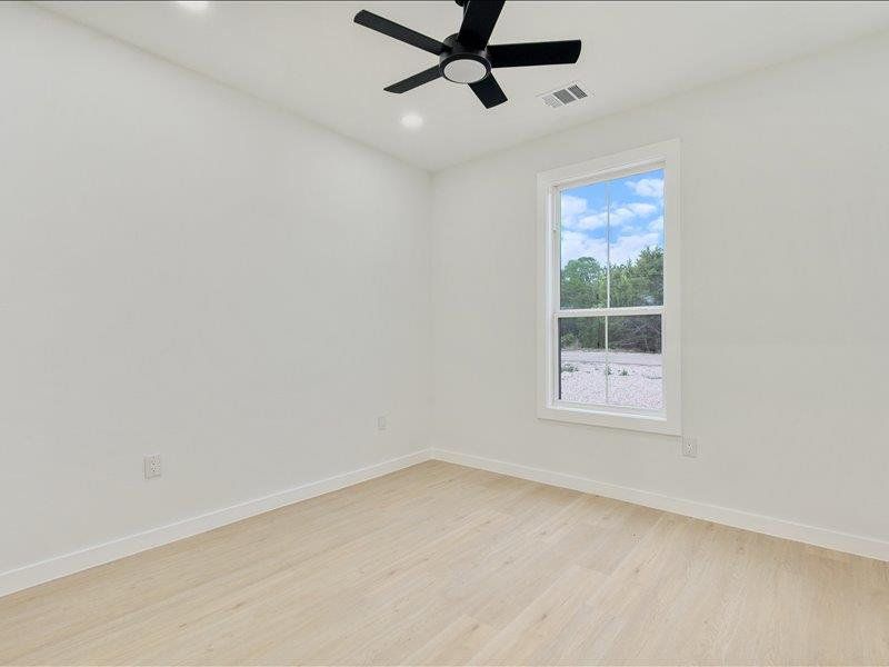 This room features light-colored flooring, a window offering natural light, and a ceiling fan