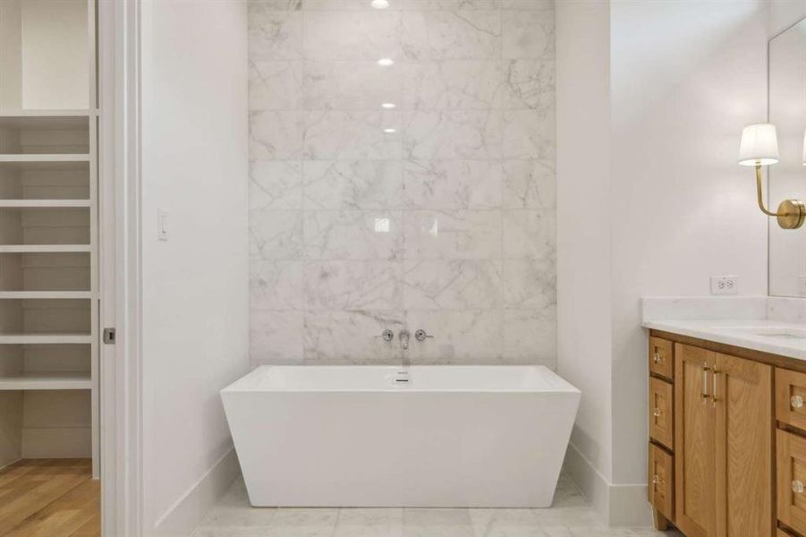 Bathroom with wood-type flooring, vanity, a bathing tub, and built in features