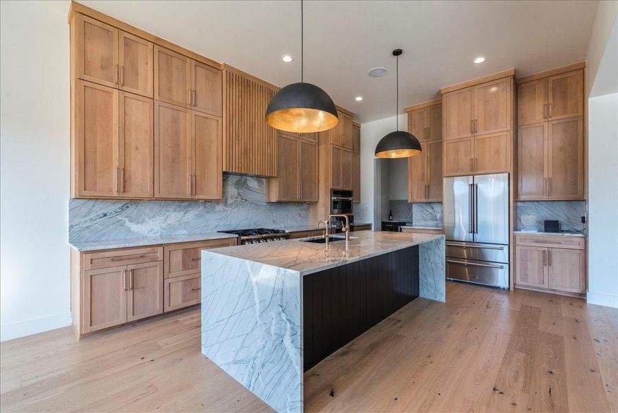 The gourmet kitchen is a chef's dream, featuring a large center island with Aurora Borealis custom quartzite and a stunning waterfall edge.