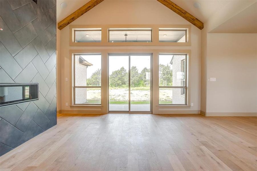 Doorway to outside with beamed ceiling, a healthy amount of sunlight, and wood finished floors