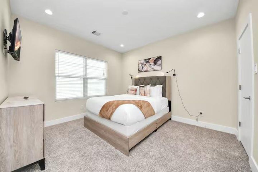 A comfortable secondary bedroom with enough space for a full bedroom setup while maintaining easy access to the nearby bath.