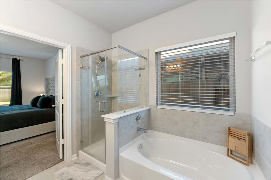 A spa-like ensuite with separate tub and shower surrounded by designer tile and a sleek frameless glass look. A spa-like ensuite with separate tub and shower surrounded by designer tile and a sleek frameless glass look.