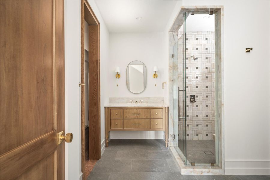 The junior suite bath is beautifully appointed with dual vanities and two separate walk-in closets, creating a private and generously proportioned suite. A natural stone-framed shower, warm wood cabinetry, and refined brass accents give the space a sophisticated, custom finish. The junior suite bath is beautifully appointed with dual vanities and two separate walk-in closets, creating a private and generously proportioned suite. A natural stone-framed shower, warm wood cabinetry, and refined brass accents give the space a sophisticated, custom finish.