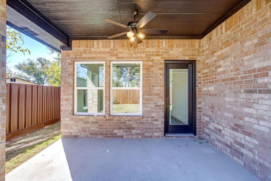 Entrance to property featuring a ceiling fan, a patio, and brick siding