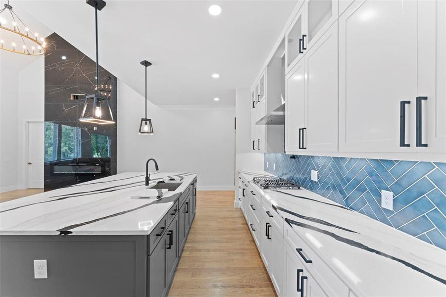 Kitchen featuring white cabinets, light wood-type flooring, glass insert cabinets, hanging light fixtures, and gray cabinetry Kitchen featuring white cabinets, light wood-type flooring, glass insert cabinets, hanging light fixtures, and gray cabinetry