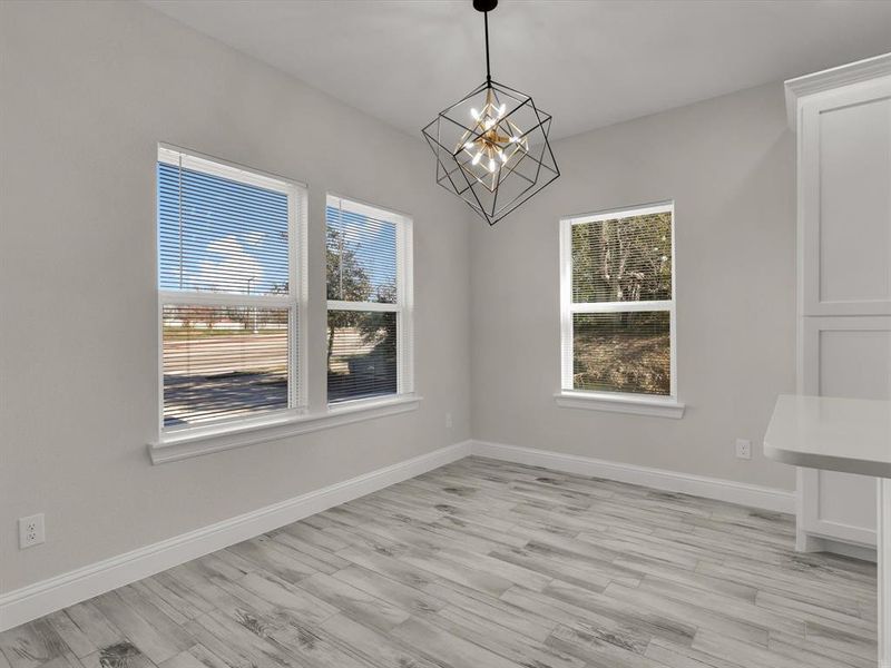 Unfurnished dining area with a wealth of natural light, light wood-type flooring, and a notable chandelier