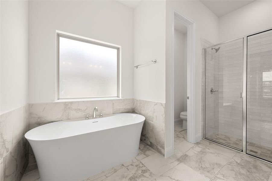 Bathroom with a soaking tub, marble finish floors, a shower stall, wainscoting, and tile walls