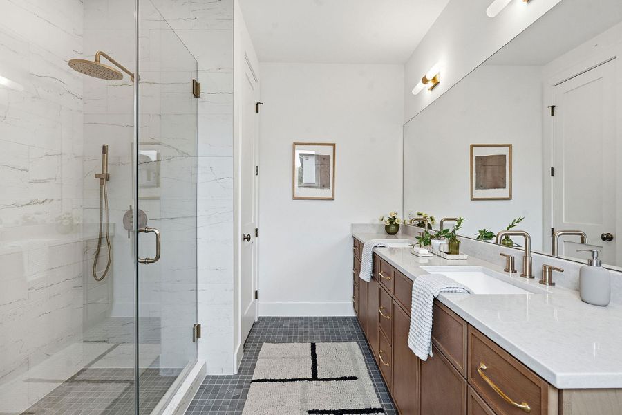 Spacious bathroom featuring a glass-enclosed shower with a rain shower head, a dual vanity with undermount sinks, and stone countertops