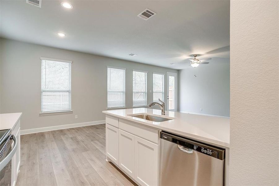 Kitchen featuring white cabinetry, dishwasher, sink, stove, and light hardwood / wood-style flooring