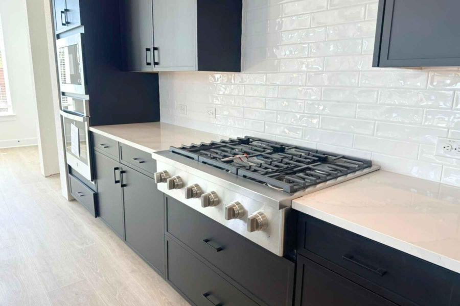 Kitchen with stainless steel appliances, tasteful backsplash, light wood-type flooring, and light stone counters Kitchen with stainless steel appliances, tasteful backsplash, light wood-type flooring, and light stone counters