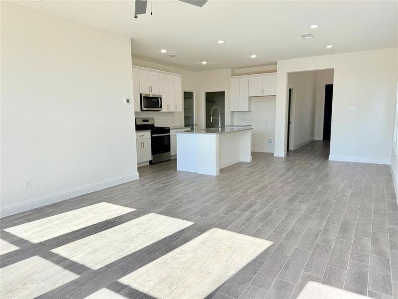 Kitchen with open floor plan, stainless steel appliances, and white cabinets