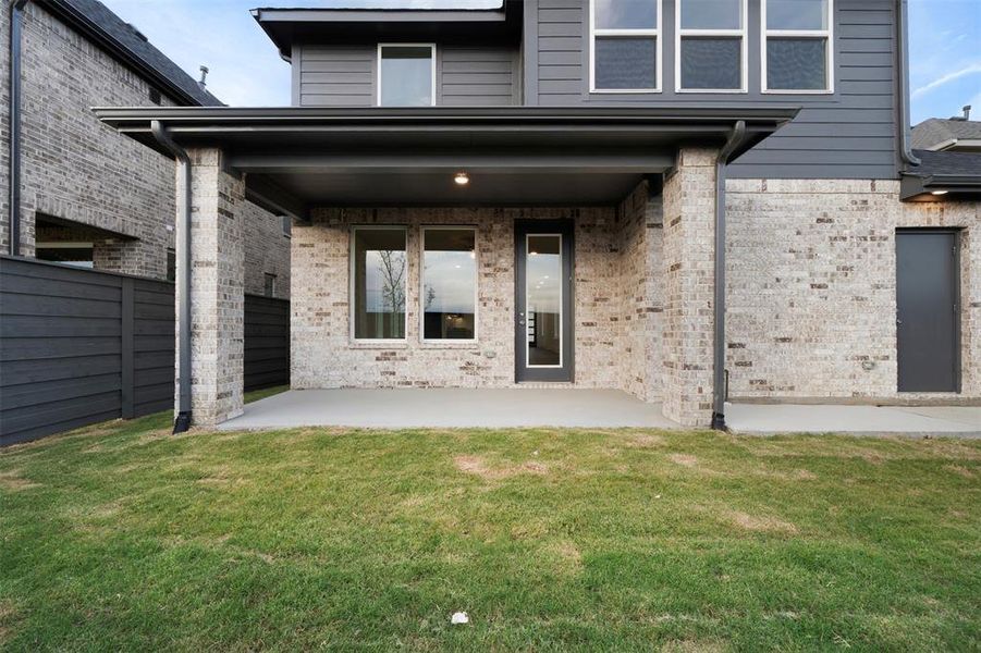 Back of property featuring a patio area and a lawn