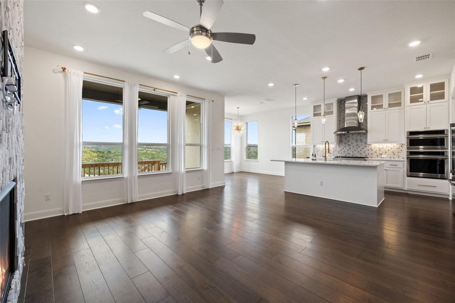 Unfurnished living room with ceiling fan with notable chandelier, visible vents, recessed lighting, and dark wood-style flooring