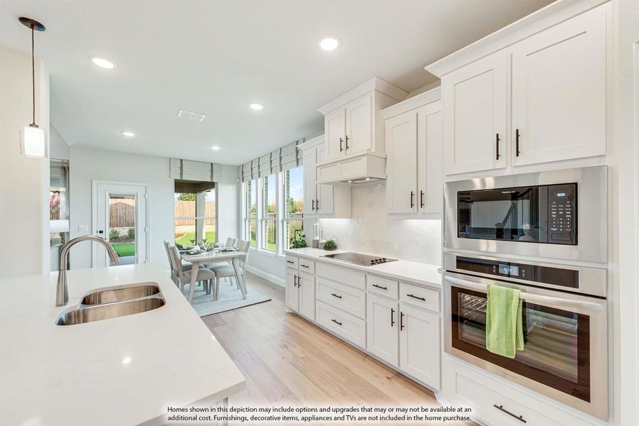 Kitchen with white cabinets, stainless steel appliances, quartz countertops, and hardwood floors open to dining area with backyard view.