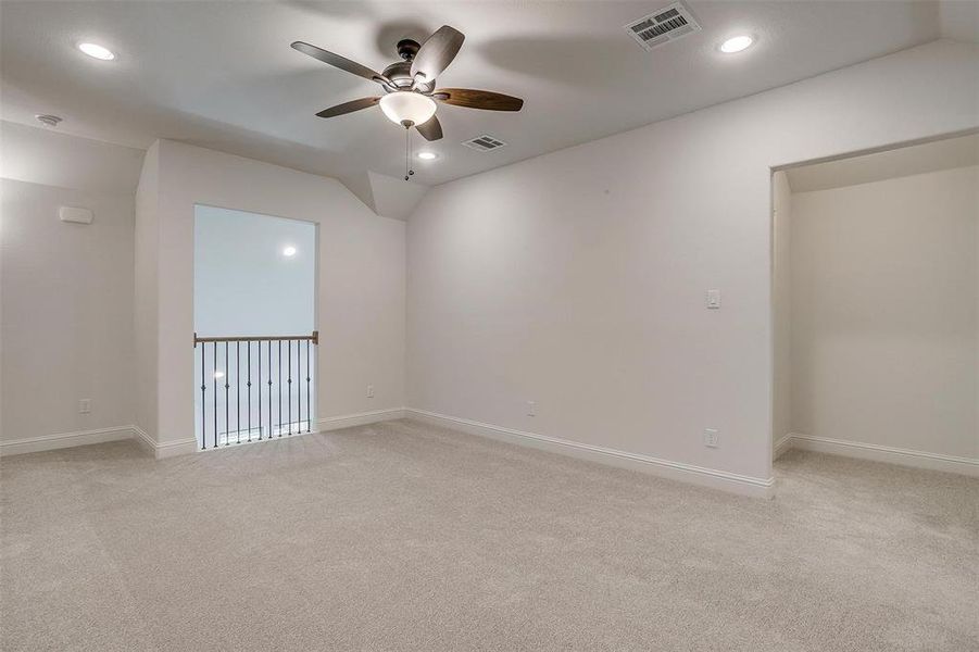 Unfurnished room featuring light colored carpet, ceiling fan, and vaulted ceiling