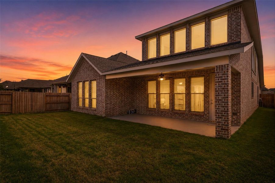 The covered back patio creates the perfect outdoor retreat for relaxing mornings, weekend barbecues, or evening gatherings. As the sun sets, the warm glow from the home creates an inviting atmosphere for year-round outdoor living.