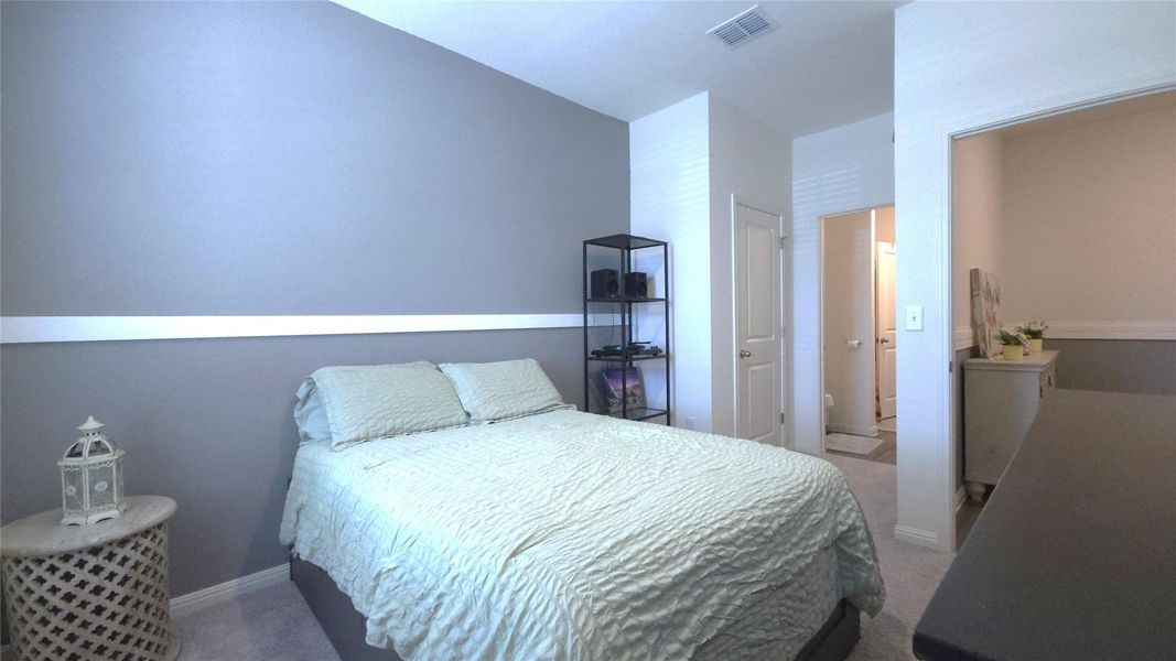 Carpeted sleeping area featuring a two-tone wall with a chair rail molding