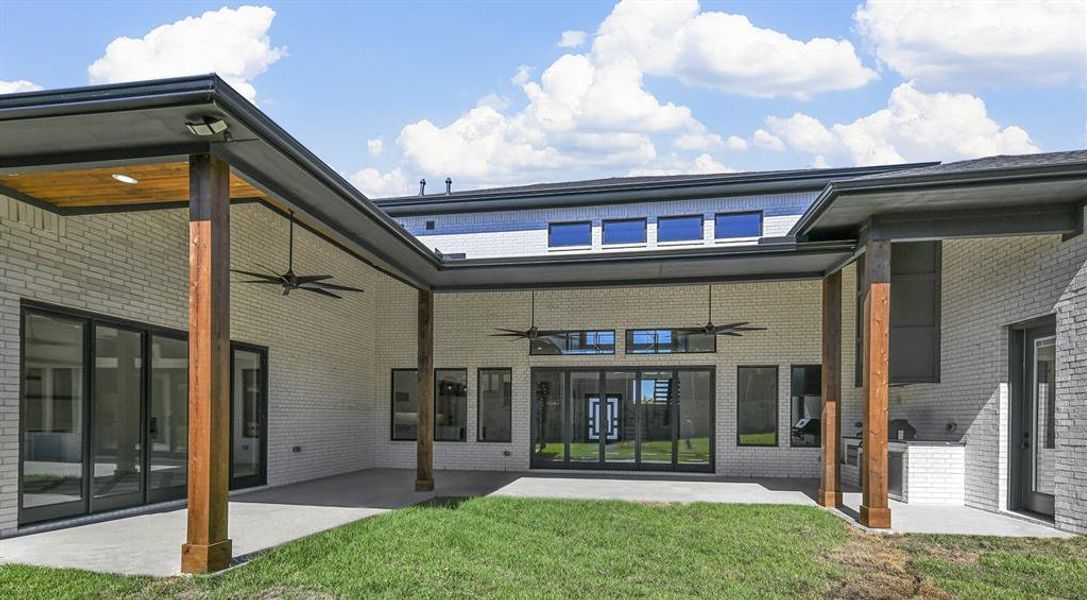 Massive backyard boasting an outdoor living center with a built-in grill & ceiling fans