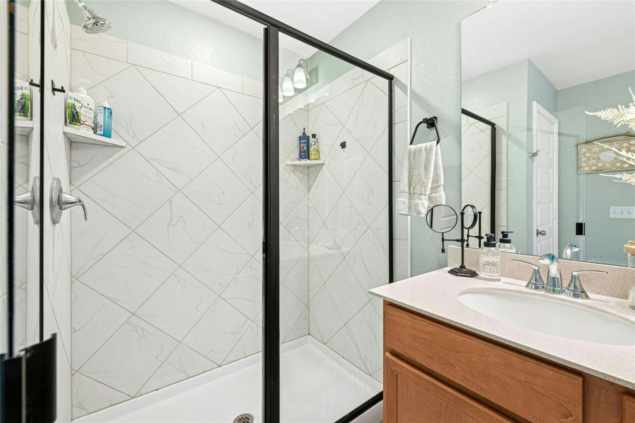 The primary bedroom features an ensuite bathroom complete with a sophisticated double vanity and a beautifully tiled shower stall with sleek glass doors, creating a refined and inviting private retreat.