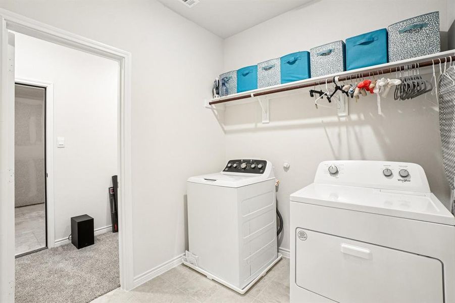 Washroom with washing machine and dryer, light carpet, and light tile patterned floors Washroom with washing machine and dryer, light carpet, and light tile patterned floors