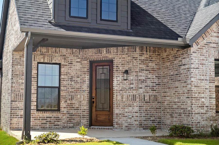 Entrance to property with brick siding and a shingled roof