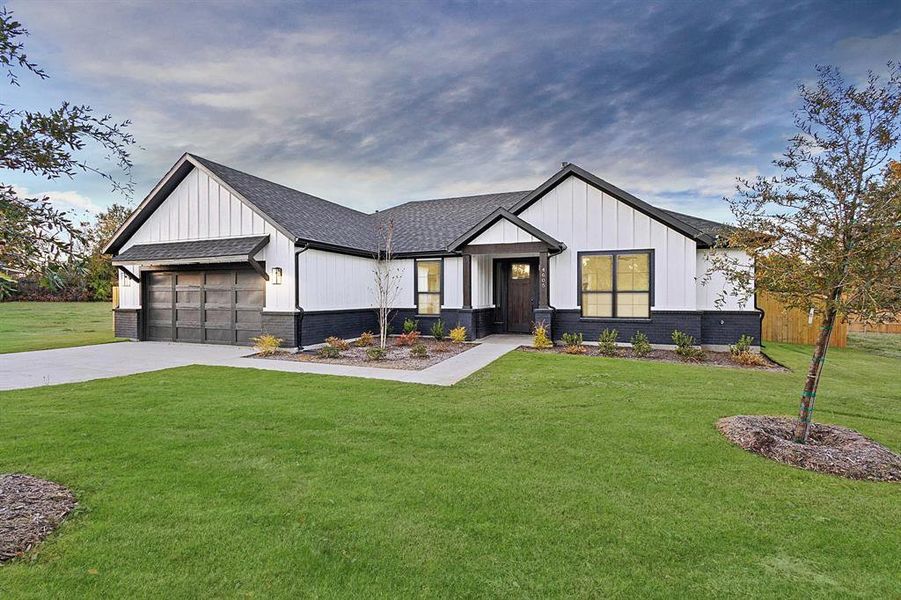 Modern inspired farmhouse with driveway, a front lawn, a garage, roof with shingles, and board and batten siding
