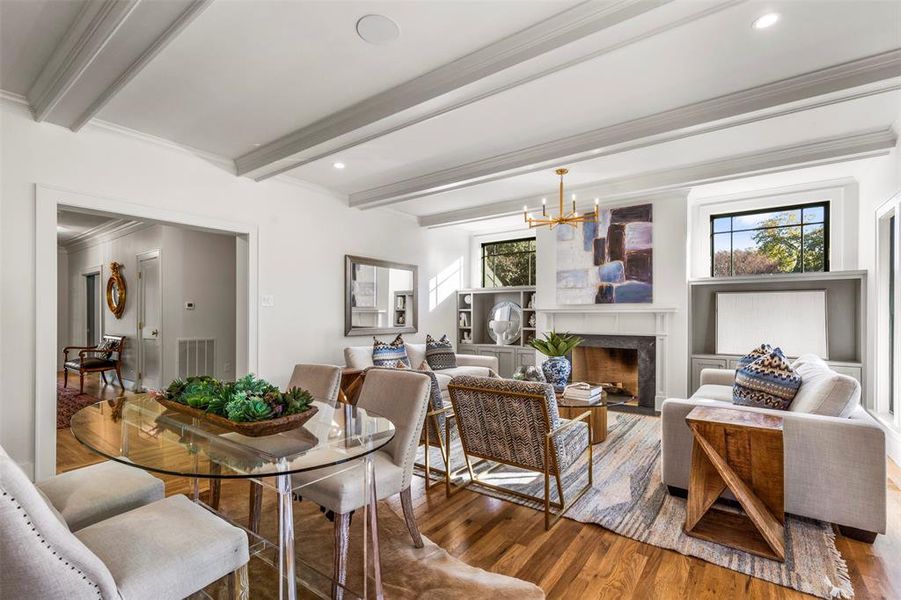 Dining area with beam ceiling, a chandelier, dark hardwood / wood-style floors, and a high end fireplace