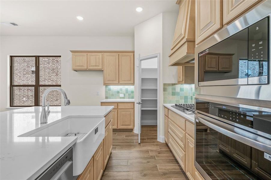 Kitchen featuring appliances with stainless steel finishes, wood tiled floors, recessed lighting, light brown cabinetry, and backsplash Kitchen featuring appliances with stainless steel finishes, wood tiled floors, recessed lighting, light brown cabinetry, and backsplash