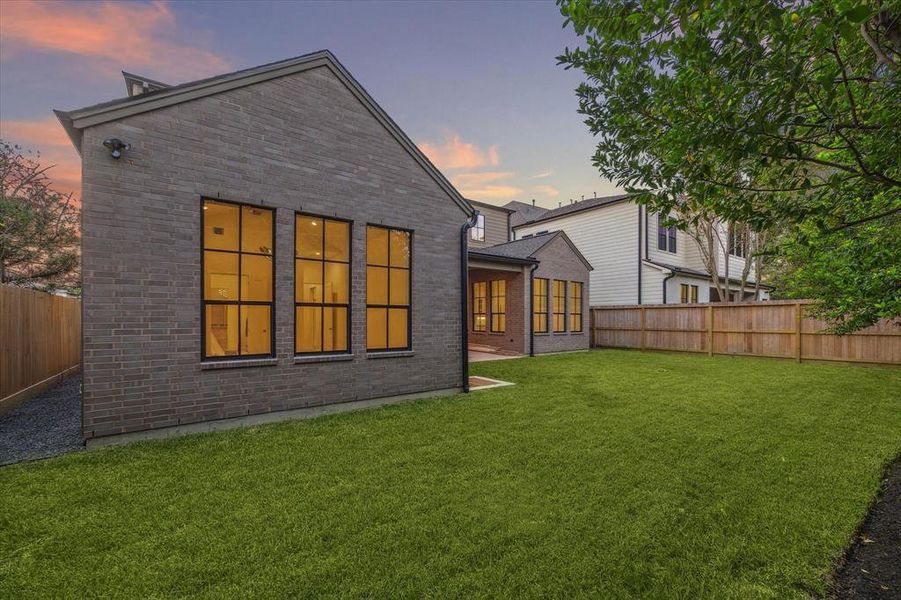 The expansive, fully-fenced backyard offers privacy and a lush green lawn, providing a great space for outdoor activities and relaxation. Multiple large windows offer picturesque views from inside the home. Plenty of space for a future pool!