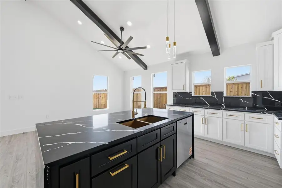 Kitchen featuring white cabinets, an island with sink, dark cabinets, pendant lighting, and beamed ceiling Kitchen featuring white cabinets, an island with sink, dark cabinets, pendant lighting, and beamed ceiling