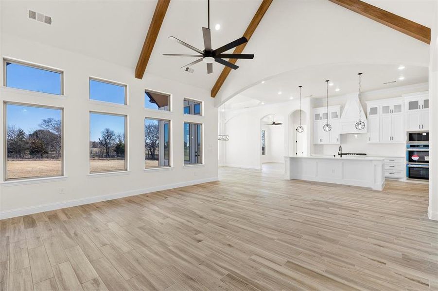 Living room with ceiling fan, high vaulted ceiling, and beamed ceiling